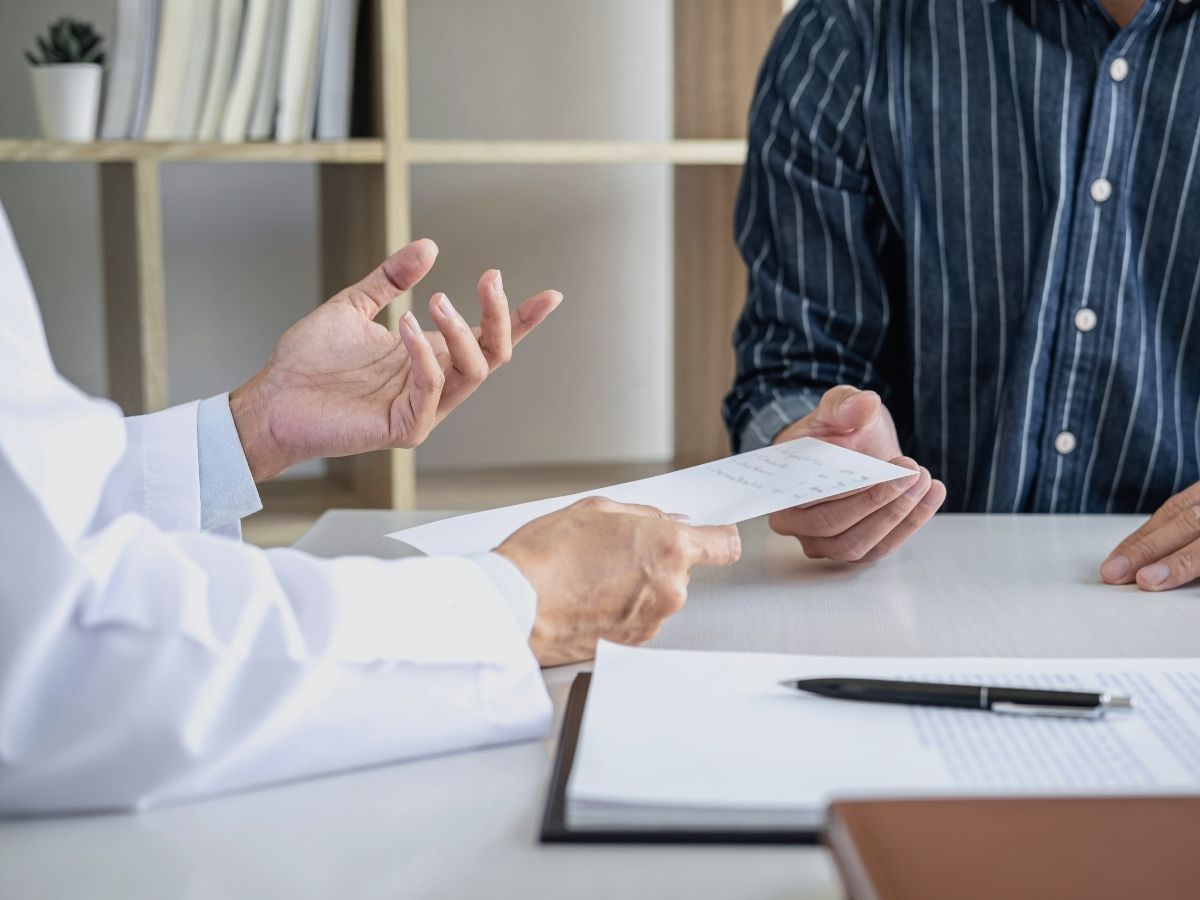 doctor-consultation-handing-prescription-to-patient.jpg Doctor handing a prescription to a patient during a medical consultation in a clinic